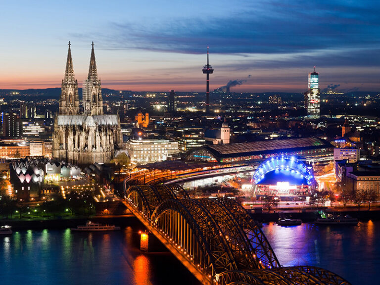 Luftaufnahme von Köln mit Dom, Rhein und beleuchteter Altstadt bei Nacht