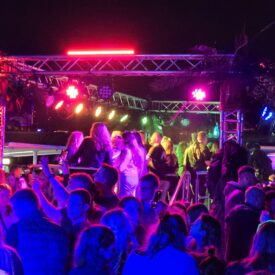 Feiernde Gäste vor der beleuchteten Bühne auf dem Schiffsdeck