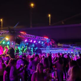 Bunt beleuchtetes Freideck mit feiernden Gästen bei Nacht