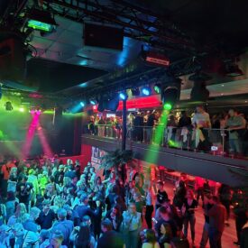 Volle Tanzfläche auf einem Partyschiff mit bunten Scheinwerfern